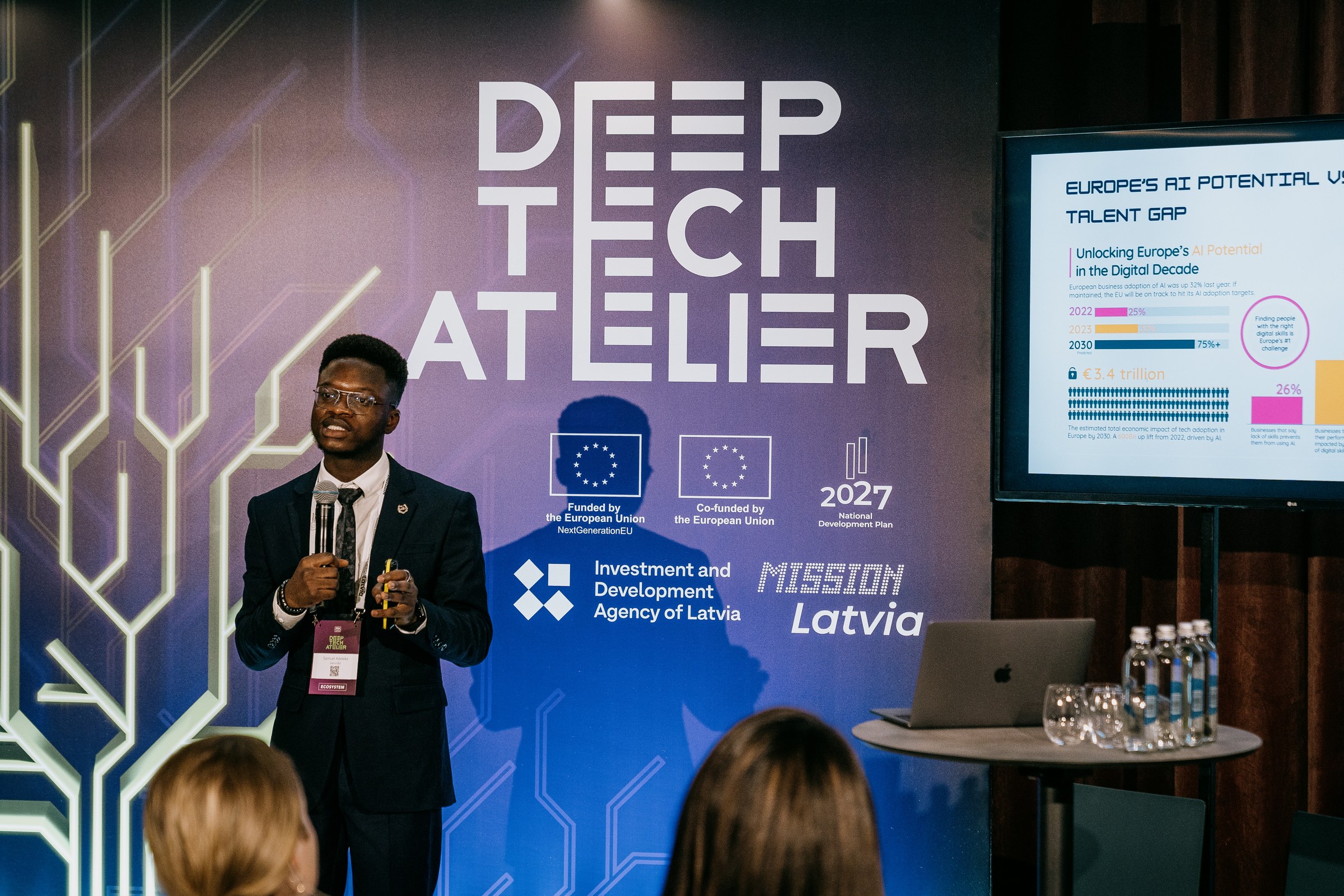 Adeleke Samuel speaking beneath the Deep Tech Atelier sign in Riga
